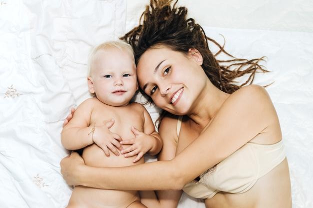 Porträt einer Mutter mit nackter Tochter, die zu Hause im Bett liegt