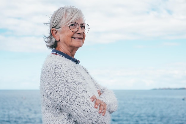 Porträt einer nachdenklichen, gutaussehenden Seniorin, die am Meer steht und wegschaut