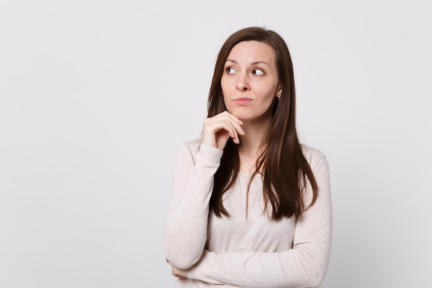 Porträt einer nachdenklichen jungen Frau in leichter Kleidung, die beiseite schaut, Handstütze auf das Kinn legen, isoliert auf weißem Wandhintergrund im Studio. Menschen aufrichtige Emotionen, Lifestyle-Konzept. Kopieren Sie Platz.