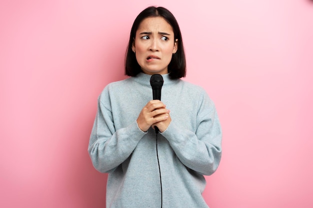 Porträt einer nervösen brünetten Frau, die nicht im Mikrofon singen möchte