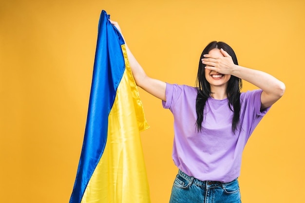 Porträt einer netten, schönen, frohen, fröhlichen Frau, die die ukrainische Flagge in den Händen hält, die Spaß hat, isoliert über gelbem, pastellfarbenem Hintergrund