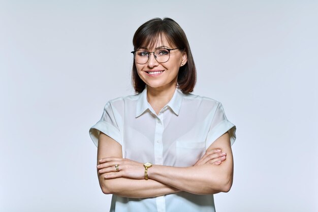 Porträt einer positiv selbstbewussten Frau mittleren Alters, die auf hellem Hintergrund in die Kamera blickt