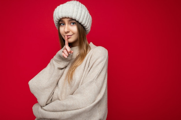 Porträt einer positiven jungen schönen dunkelblonden Frau mit aufrichtigen Emotionen, die beigefarbenen Pullover trägt