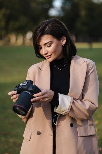 Porträt einer professionellen Fotografin mit DSLR-Kamera, die im Park spazieren geht