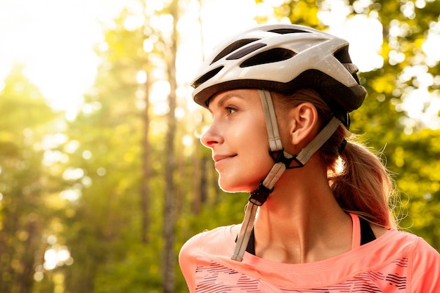 Porträt einer Radfahrerin mit Helm auf dem Hintergrund eines grünen Waldes