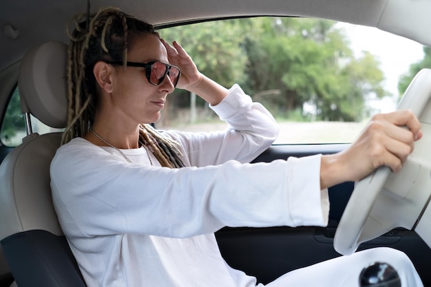 Porträt einer Rasta-Frau mit einer Brille, die ein Auto fährt