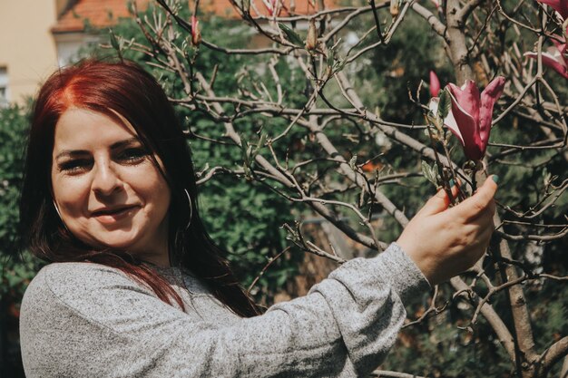 Foto porträt einer reifen frau, die eine blume an einer pflanze berührt