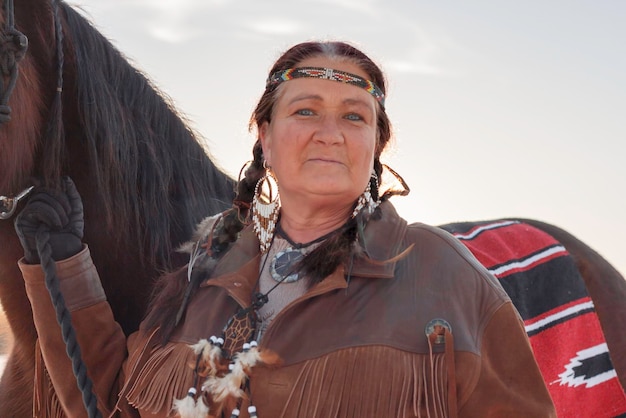 Foto porträt einer reifen frau in traditioneller kleidung, die neben einem pferd steht