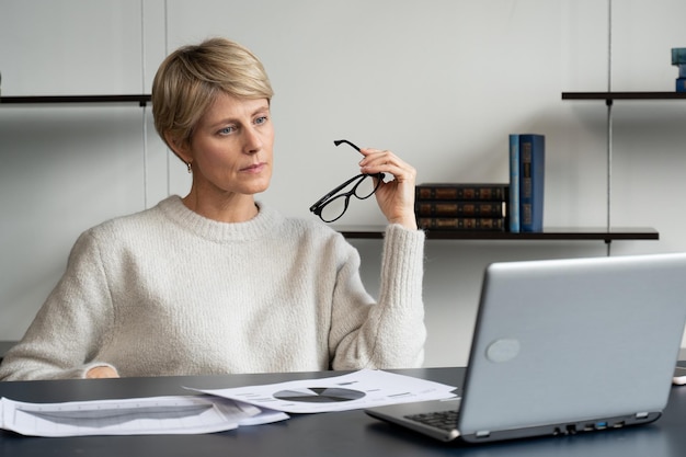 Porträt einer reifen Geschäftsfrau, die an einem Laptop am Arbeitsplatz im Büro arbeitet, hebt sie ab