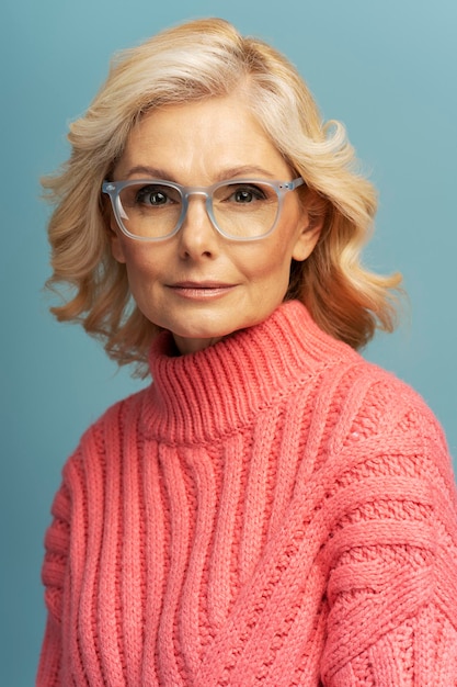 Porträt einer reifen Geschäftsfrau mit Brille, die isoliert auf blauem Hintergrund in die Kamera blickt