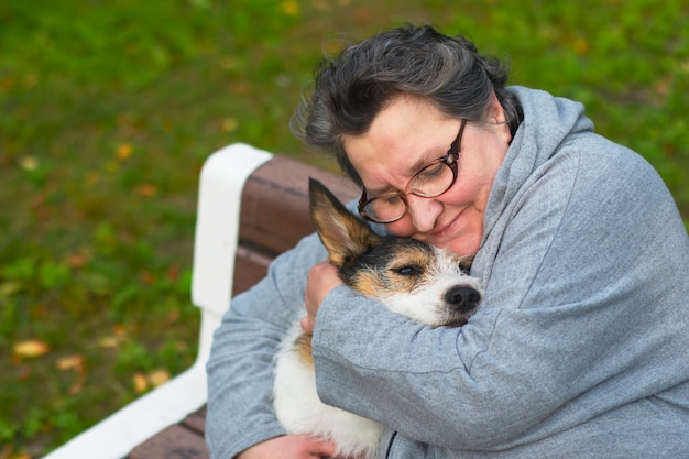 Porträt einer Rentnerin, die ihren Hund umarmt