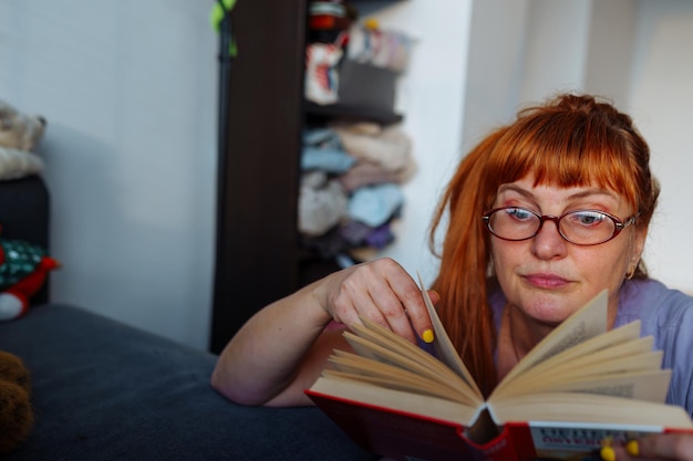 Porträt einer rothaarigen Frau, die einen Roman liest