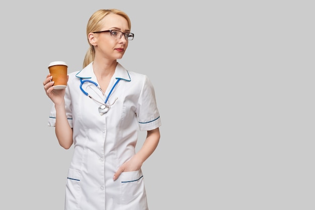 Porträt einer Ärztin, die Pappbecher Kaffee hält