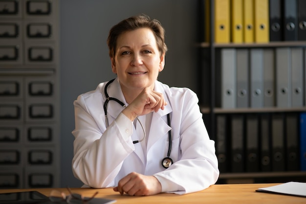 Porträt einer Ärztin mittleren Alters trägt einen weißen Arztkittel mit einem Stethoskop um den Hals