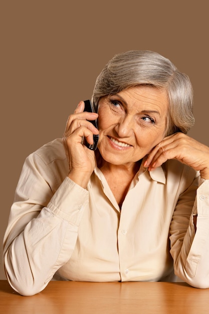 Porträt einer schönen älteren Frau, die zu Hause am Telefon spricht