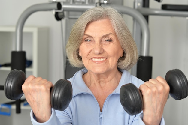 Porträt einer schönen älteren Frau in einem Fitnessstudio mit Hanteln