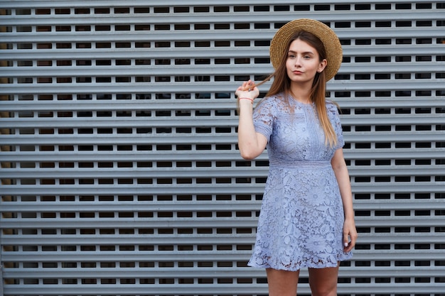 Porträt einer schönen anmutigen Frau im eleganten Hut und im blauen Spitzenkleid.