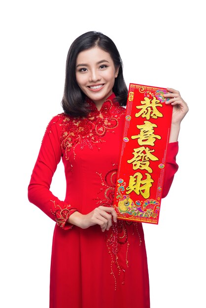 Porträt einer schönen asiatischen Frau auf traditionellem Festivalkostüm Ao Dai, das Neujahrsrollen Tet-Feiertag zeigt. Mondneujahr. Text bedeutet Glück und Reich werden.