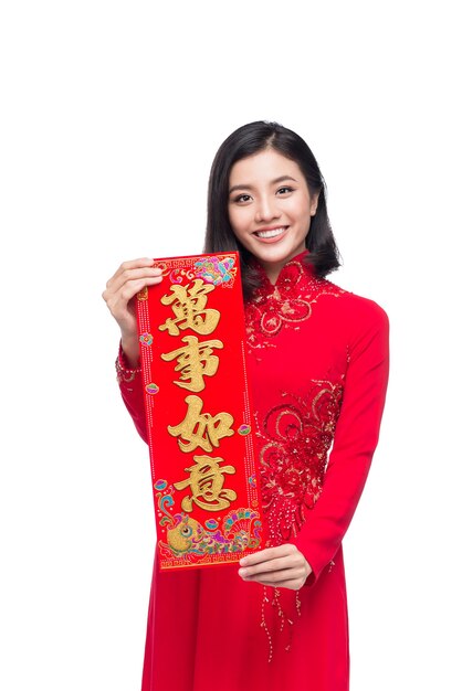 Porträt einer schönen asiatischen Frau auf traditionellem Festivalkostüm Ao Dai, das Neujahrsrollen Tet-Feiertag zeigt. Mondneujahr. Text bedeutet Glück und Reich werden.