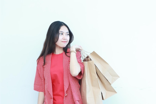 Porträt einer schönen asiatischen Frau, die ein rotes Outfit trägt und viele Einkaufstaschen trägt
