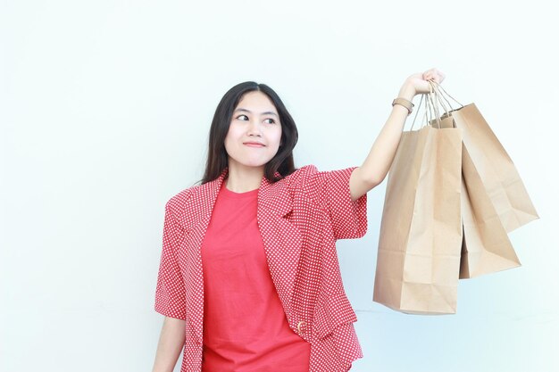 Porträt einer schönen asiatischen Frau, die ein rotes Outfit trägt und viele Einkaufstaschen trägt