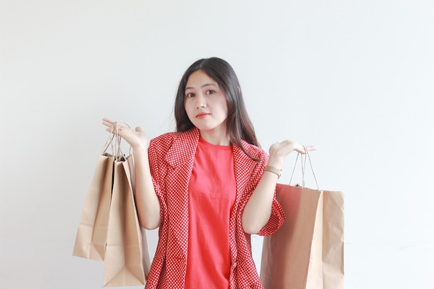 Porträt einer schönen asiatischen Frau, die ein rotes Outfit trägt und viele Einkaufstaschen trägt