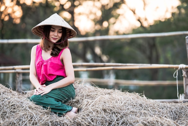 Porträt einer schönen asiatischen Frau, die ein thailändisches Landkleid auf dem Feld trägtThailänder