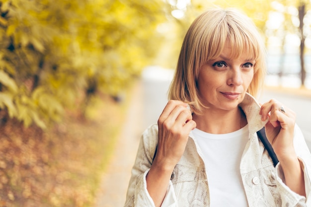 Porträt einer schönen blonden erwachsenen Frau im Herbstpark auf dem Naturspaziergang im Freien