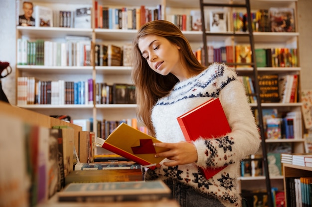 Porträt einer schönen brünetten frau, die nach einem buch im laden sucht