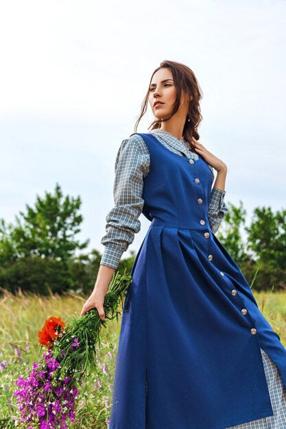 Porträt einer schönen brünetten Frau im blauen Kleid auf dem Feld