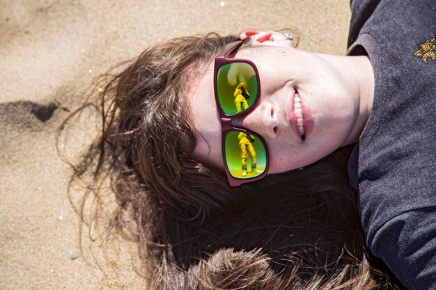 Foto porträt einer schönen frau, die auf dem sand liegt