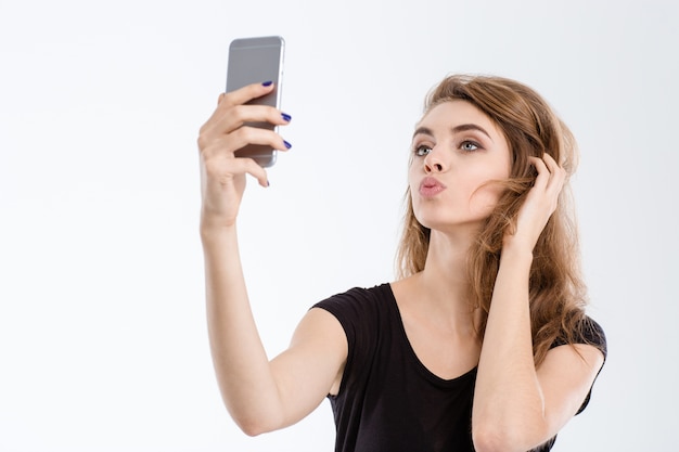 Porträt einer schönen frau, die ein selfie-foto auf dem smartphone macht, isoliert auf weißem hintergrund