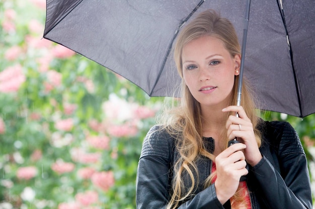 Porträt einer schönen Frau, die einen Regenschirm am Bürgersteig hält