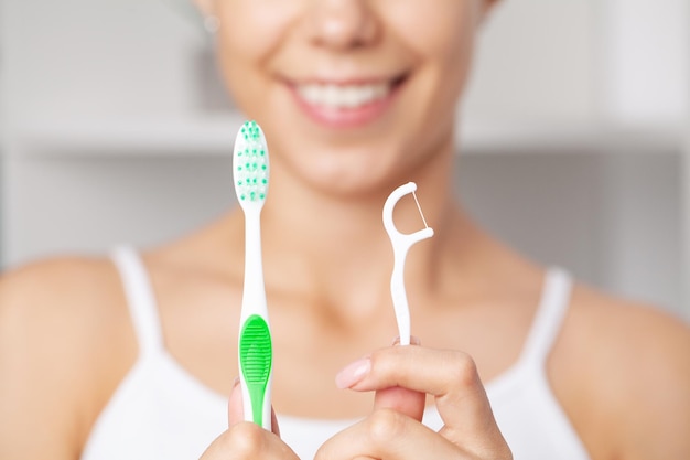 Porträt einer schönen Frau, die Zähne mit Zahnseide putzt