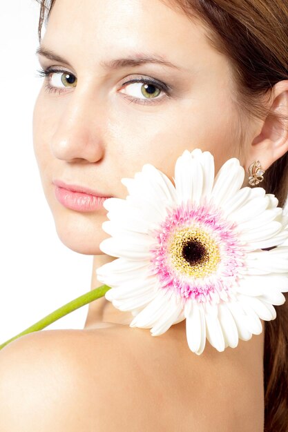 Porträt einer schönen Frau mit hellem Make-up, die rosa Gänseblümchen in den Händen hält