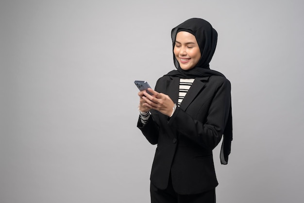 Porträt einer schönen Frau mit Hijab mit Mobiltelefon auf weißem Hintergrund