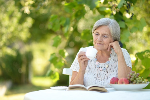 Porträt einer schönen Frau mittleren Alters, die mit einem Buch am Tisch sitzt