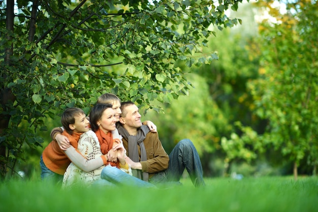 Porträt einer schönen glücklichen Familie, die im Herbstpark sitzt