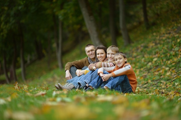 Porträt einer schönen glücklichen Familie, die im Herbstpark sitzt