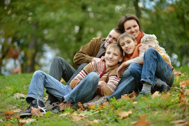 Porträt einer schönen glücklichen Familie, die im Herbstpark sitzt