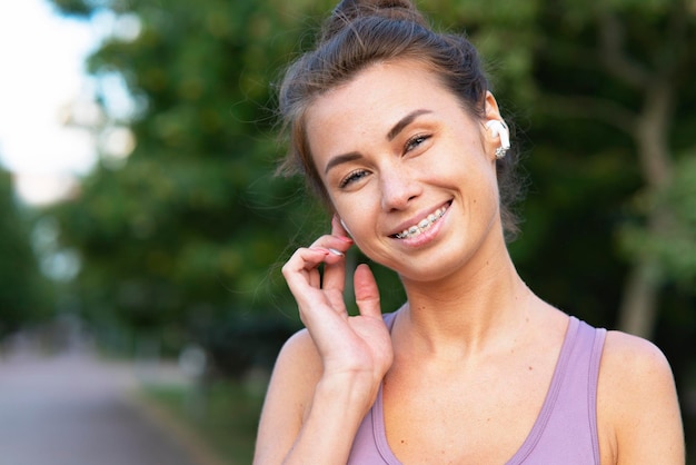 Porträt einer schönen, glücklichen jungen Frau, die beim Sportjoggen über Bluetooth-Kopfhörer spricht