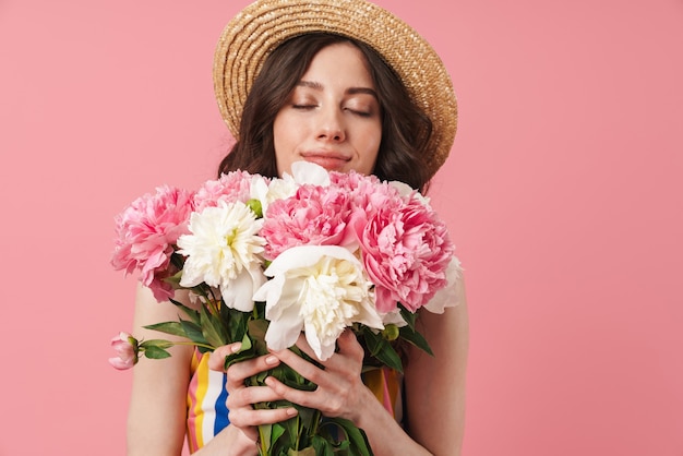 Porträt einer schönen glücklichen jungen süßen Frau, die isoliert über rosa Wand mit Blumen posiert