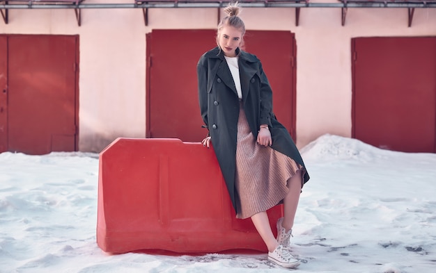 Porträt einer schönen Hippie-Blondine, die im weißen T-Shirt und im Kleid sitzen auf blauer Couch tragen