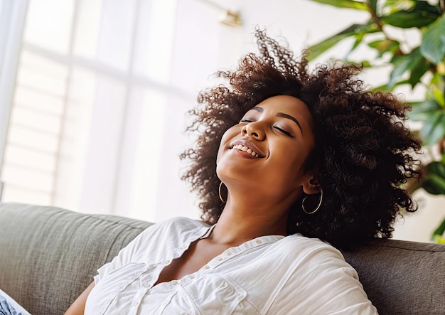 Porträt einer schönen jungen afroamerikanischen Frau, die sich zu Hause auf dem Sofa entspannt