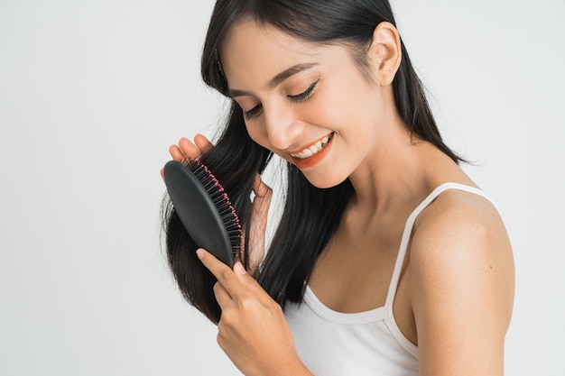 Porträt einer schönen jungen asiatischen Frau, die ihr langes glattes Haar kämmt