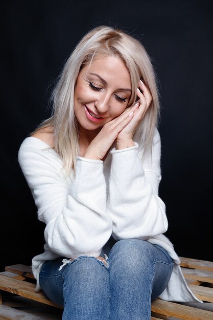 Porträt einer schönen jungen attraktiven Frau in einem weißen Pullover mit blauen Augen und langen blonden Haaren.