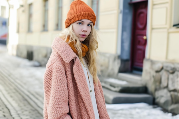 Porträt einer schönen jungen blonden Frau in einem rosa Mantel und Hut auf der Straße