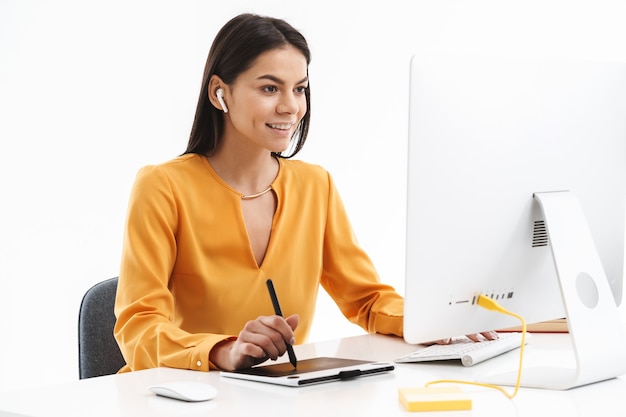 Porträt einer schönen jungen Designerin, die einen grafischen Tablet-Computer und einen Eingabestift verwendet, während sie in einem hellen Büro arbeitet