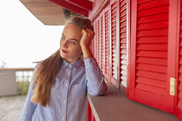 Porträt einer schönen jungen Frau auf dem Hintergrund einer roten hölzernen Wand