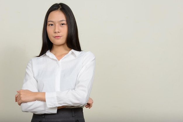Porträt einer schönen jungen Frau, die an einer weißen Wand steht